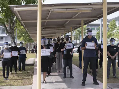 Dokter kontrak memegang plakat saat berpartisipasi dalam aksi mogok di Rumah Sakit Sungai Buloh di Selangor, Malaysia, Senin (26/7/2021). Ratusan dokter melakukan aksi mogok kerja dari rumah sakit pemerintah Malaysia pada (26/7). (AFP/Arif Kartono)