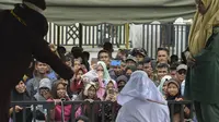 Warga menonton hukum cambuk yang dilakukan kepada Tjia Nyuk Hwa di luar Masjid Babussalam, Banda Aceh, Aceh, Indonesia, Selasa (27/2). Tjia Nyuk Hwa dicambuk sebanyak tujuh kali, sedangkan suaminya enam kali cambukan. (AFP FOTO/CHAIDEER MAHYUDDIN)
