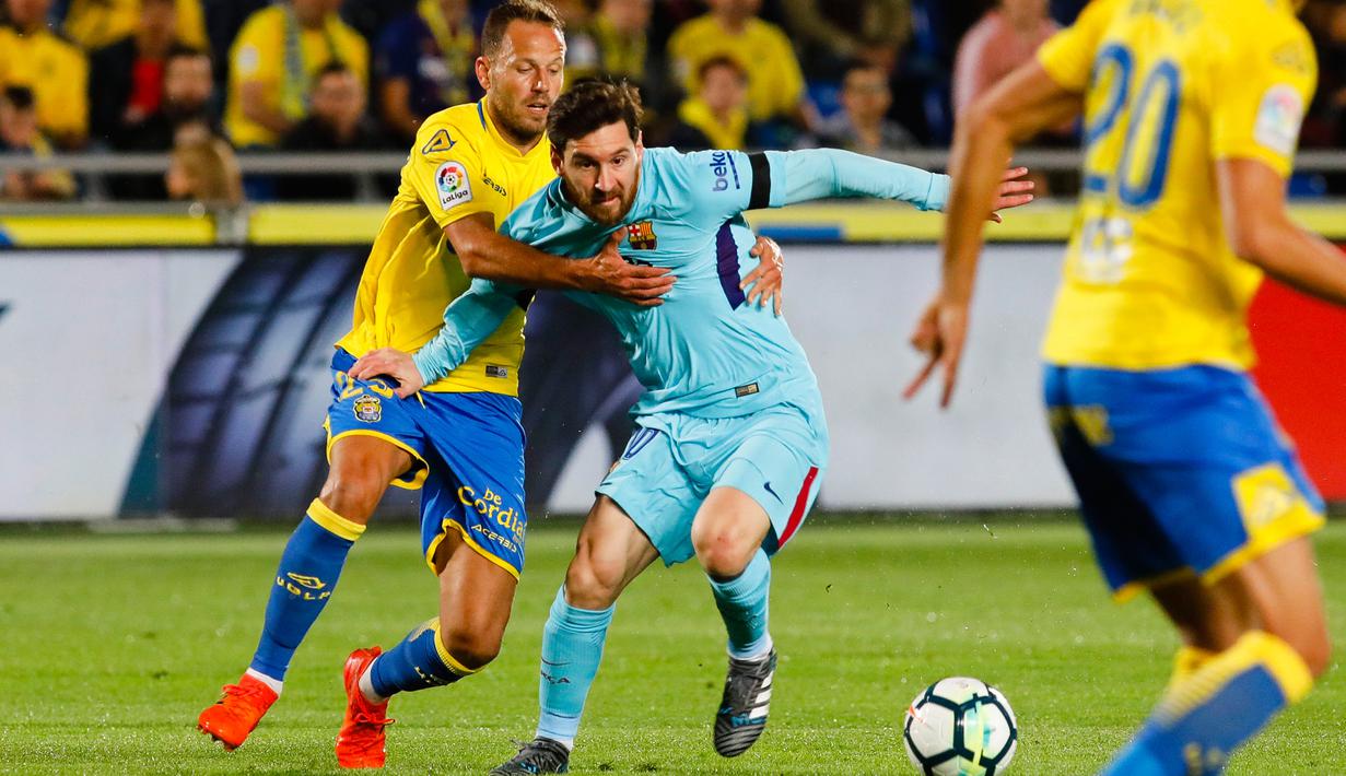 Pemain Barcelona Lionel Messi berebut bola dengan pemain Las Palmas, Rafael Castell pada jornada ke-26 La Liga 2017-2018 di Estadio Gran Canaria, Kamis (1/3). Barcelona gagal menang karena tuan rumah menahan imbang dengan skor 1-1. (AP/Lucas de Leon)