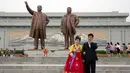 Pasangan pengantin berdiri di dekat patung perunggu raksasa pemimpin Korea Utara Kim Il Sung dan Kim Jong Il dalam peringatan berakhirnya Perang Dunia II dan pembebasan dari kolonial Jepang di Pyongyang, Korut, Rabu (15/8). (AP Photo/Ng Han Guan)