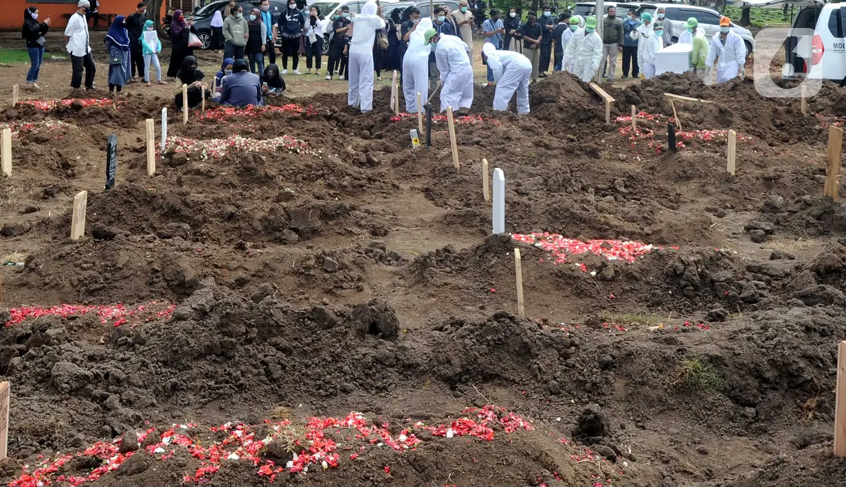 Keluarga menyaksikan pemakaman jenazah korban COVID-19 di TPU Tegal Alur, Jakarta, Kamis (17/12/2020). Hingga hari ini, intensitas pemakamanan korban covid-19 di DKI masih tinggi dengan rata-rata yang dimakamkan mencapai 30 hingga 38 jenazah per hari. (merdeka.com/Arie basuki)