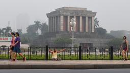 Orang-orang berolahraga di depan mausoleum Ho Chi Minh di Hanoi setelah kegiatan olahraga outdoor diizinkan menyusul pelonggaran pembatasan Covid-19, Selasa (28/9/2021). Sejauh ini, 94 persen dari populasi orang dewasa Hanoi telah menerima satu suntikan vaksin. (Nhac NGUYEN/AFP)