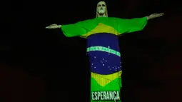 Patung Christ the Redeemer atau Yesus sang Penebus yang populer di dunia menyala dengan gambar bendera Brasil bertuliskan 'harapan' pada hari Paskah di Rio de Janeiro, Brasil, Minggu (12/4/2020). Pertunjukkan itu bentuk dukungan dan semangat untuk melawan pandemi COVID-19. (AP/Silvia Izquierdo)