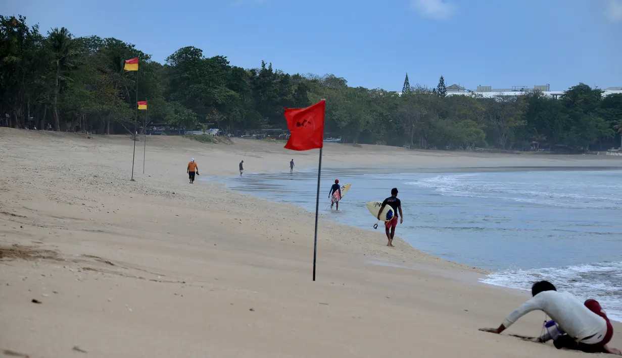 <p>Anak-anak berjalan dengan papan selancar mereka di pantai Kuta di pulau resor Bali (4/10/2021). Setiap tamu kedatangan internasional ada ketentuan dan persyartan yaitu wajib karantina, tes dan kesiapan satuan tugas. (AFP/Sony Tumbelaka)</p>
