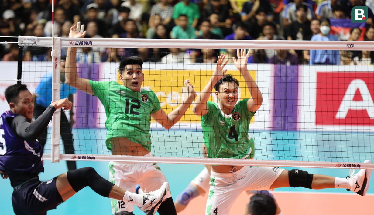 Reaksi dua pemain tim bola voli putra Indonesia, Rivan Nurmulki (kiri) dan Hendra Kurniawan setelah memblok spike yang dilepaskan pemain Kamboja pada laga ketiga Grup A SEA Games 2023 di Olympic Complex Indoor Main Hall, Phnom Penh, Kamboja, Sabtu (6/5/2023). Tim bola voli Putra Indonesia menang 3-0 (25-18, 25-21, 25-16) dan memastikan lolos ke semifinal sebagai juara Grup A. (Bola.com/Abdul Aziz)