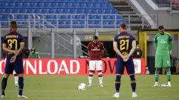 Para pemain AC Milan dan AS Roma mengheningkan cipta sebelum bertanding pada pertandingan Serie A di Stadion San Siro, Milan, Minggu (28/6/2020). AC Milan naik ke posisi 7 klasemen dengan 42 poin usai mengalahkan AS Roma 2-0. (AP Photo/Luca Bruno)