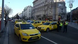 Petugas keamanan berjaga selama pemblokiran yang dilakukan Sejumlah Sopir taksi yang menolak layanan aplikasi  Uber di Budapest, Hongaria, (18/1). Tuntutan mereke berisi tentang resiko adanya aplikasi Uber terhadap pekerjaan mereka.  (AFP / Ferenc ISZA)