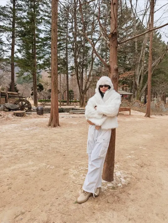 Ia padukan long sleeve dengan syal dan hooded jaket wol yang super tebal dan celana kargo. Sling bag dan boots nude lengkapi busananya [@miktambayong]