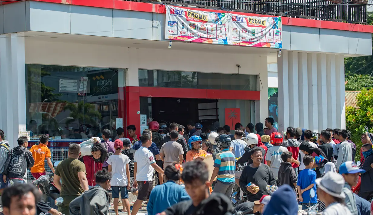 Warga menjarah kebutuhan pokok dari toko swalayan setelah gempa kuat dan tsunami mengguncang Kota Palu di Sulawesi Tengah, Minggu (30/9). Warga terpaksa mengambil karena mereka juga membutuhkan makanan dan air bersih. (AFP PHOTO/BAY ISMOYO)