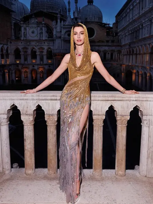 Anne Hathaway mengenakan sequined hooded gown berwarna emas dari koleksi FW23 Atelier Versace saat menghadiri Bulgari's jewelry show di Venice, Italia. [Twitter]