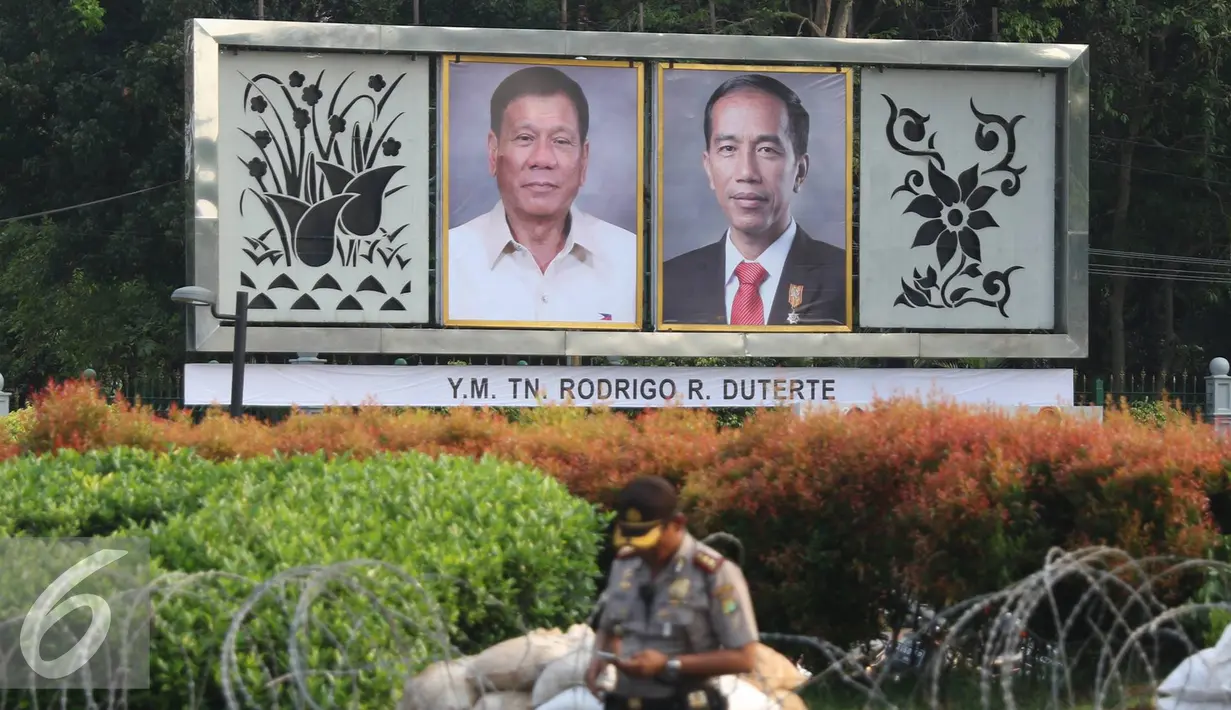 Polisi melintas di depan foto Jokowi dan Duterte di Taman Pandang Istana, Jakarta, Kamis (8/9). Rencananya Duterte akan berkunjung ke Indonesia pada Jumat (9/9). (Liputan6.com/Immanuel Antonius)