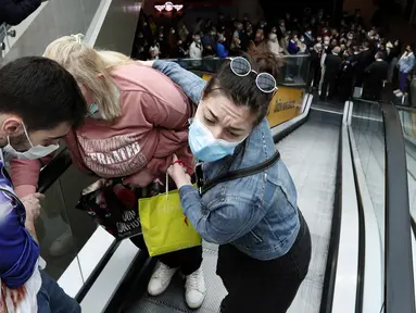 Seorang wanita dibantu naik eskalator saat orang antre vaksinasi dan menjadi salah satu orang yang menerima kupon belanja, di pusat perbelanjaan Usce di Beograd, Kamis (6/5/2021). Pemerintah Serbia menawarkan uang Rp 430 ribu bagi warganya yang divaksinasi sebelum akhir Mei. (AP/Darko Vojinovic)