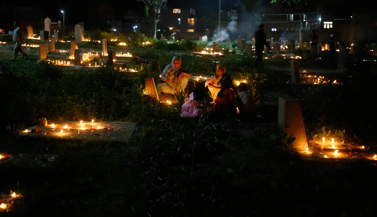 Sejumlah warga Kashmir menyalakan lilin di pemakaman keluarga dan saudara mereka saat memperingati Shab-e-Barat di pinggiran Srinagar, Kashmir (1/5). Selain itu mereka juga berdoa untuk sanak keluarga mereka. (AP Photo / Mukhtar Khan)