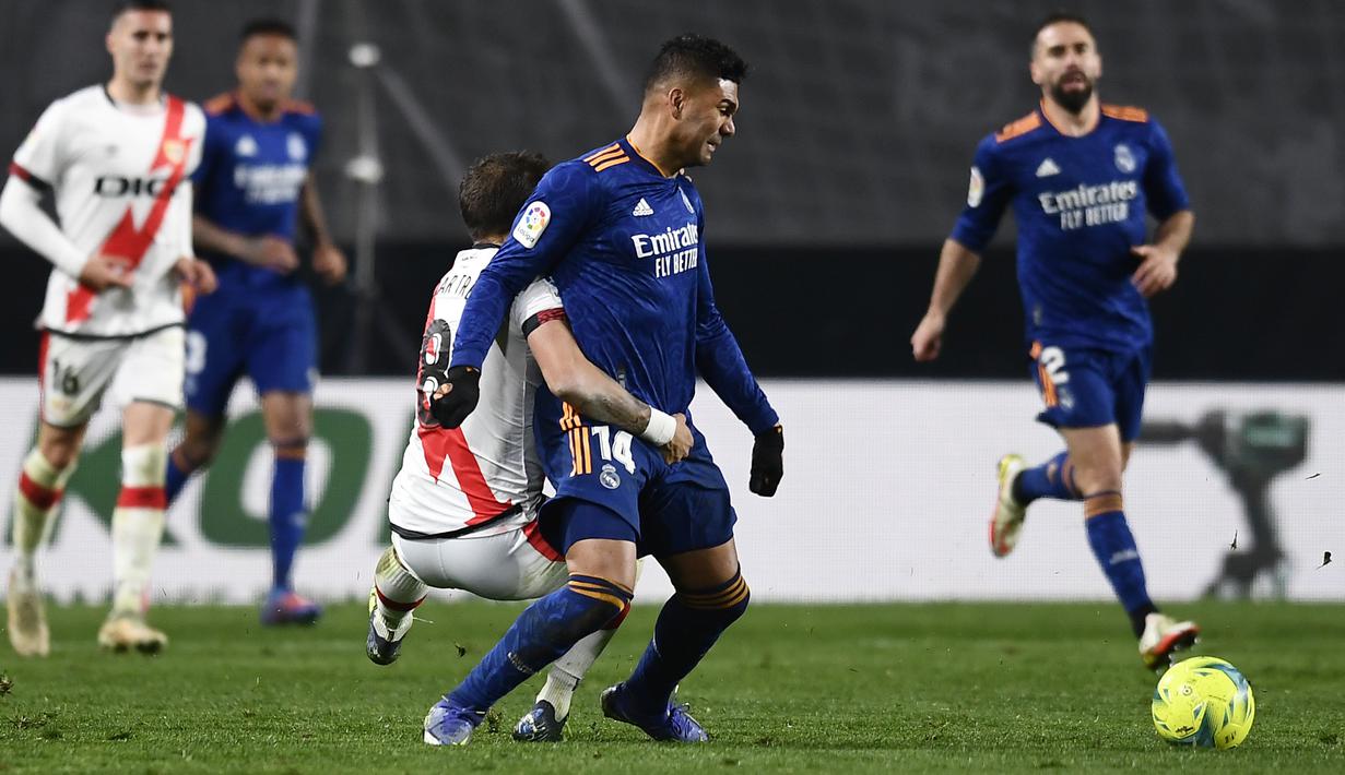 Gelandang Real Madrid, Casemiro (tengah) berebut bola dengan pemain Rayo Vallecano, Oscar Trejo pada pertandingan La Liga Spanyol di stadion Vallecas di Madrid, Spanyol, Minggu (27/2/2022). Real Madrid menang tipis atas Rayo Vallecano 1-0. (AP Photo/Jose Breton)