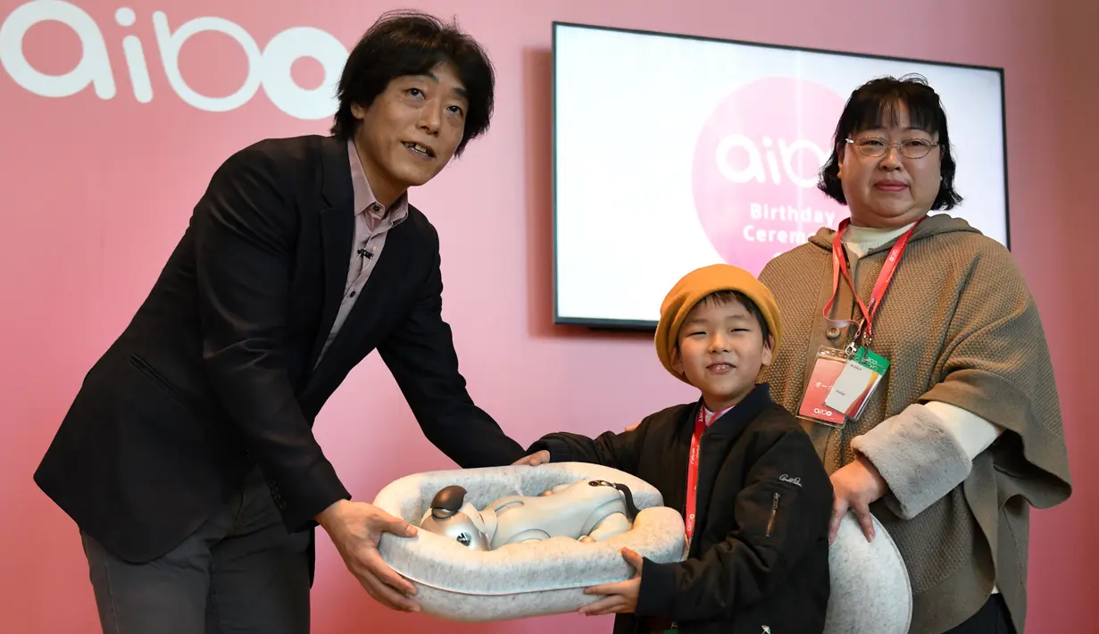 Kepala Kelompok Usaha Robotika AI, Izumi Kawanishi (kiri) menyerahkan sebuah tempat yang berisi robot anjing dari Sony, Aibo kepada pemilik baru yang telah membeli pada acara peresmian di Tokyo, Jepang (11/1). (AFP Photo/Kazuhiro Nogi)