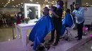 Seorang perempuan memotong rambutnya saat acara Bulan Peduli Kanker Payudara di sebuah mal di Caracas, Venezuela, Sabtu (16/10/2021). Rambut yang dipotong akan disumbangkan untuk membuat wig bagi pasien kanker. (AP Photo/Ariana Cubillos)
