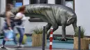 Pejalan kaki melewati replika dinosaurus Plateosaurus seukuran aslinya di pusat kota Bochum, Jerman (12/8/2019). Pameran ini menampilkan 33 replika dinosaurus di sekitar pusat kota, berada di Bochum. (AP Photo/Martin Meissner)