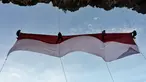 Sekelompok mahasiswa mengibarkan bendera Merah Putih berukuran besar menjelang perayaan Hari Ulang Tahun ke-77 Republik Indonesia di Pantai Lhoknga, Aceh, 16 Agustus 2022. Pengibaran bendera Merah Putih berukuran besar yang dilakukan pada sebuah tebing ini untuk memeriahkan Hari Ulang Tahun ke-77 Republik Indonesia. (CHAIDEER MAHYUDDIN/AFP)