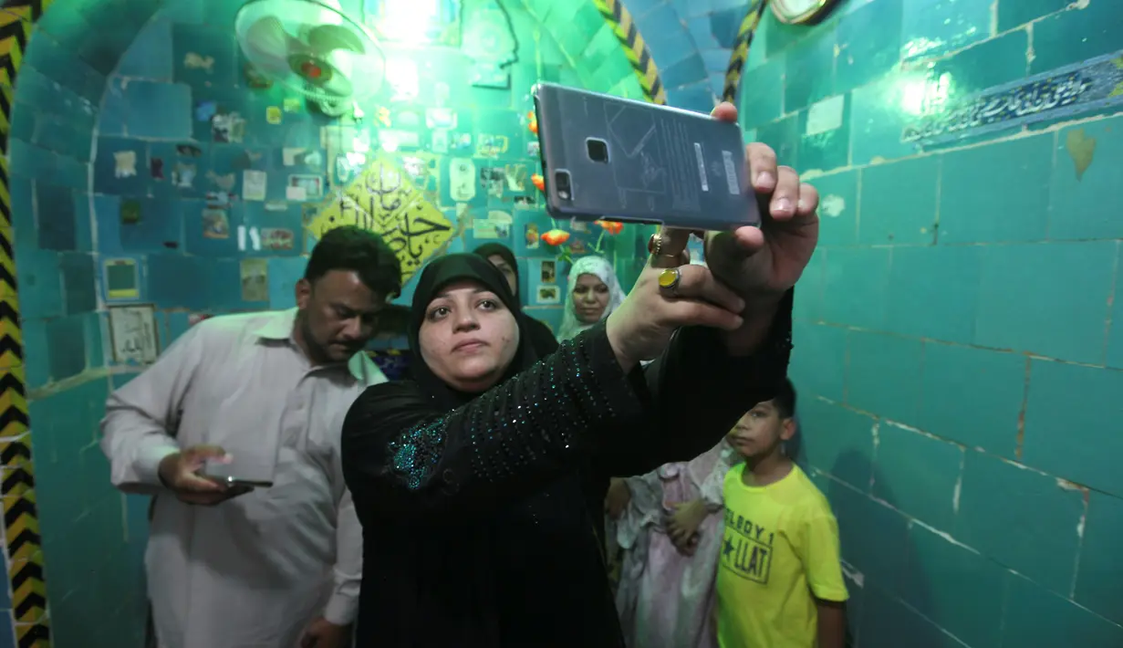Seorang wanita berselfie di dalam tempat suci Imam Mahdi di pemakaman Wadi al-Salam, di Najaf, selatan Baghdad, Irak, 1 Agustus 2016. Kota Najaf yang dijuluki 'kota orang mati' ini membentang hingga 10 km di sepanjang lembah. (REUTERS / Alaa Al-Marjani)