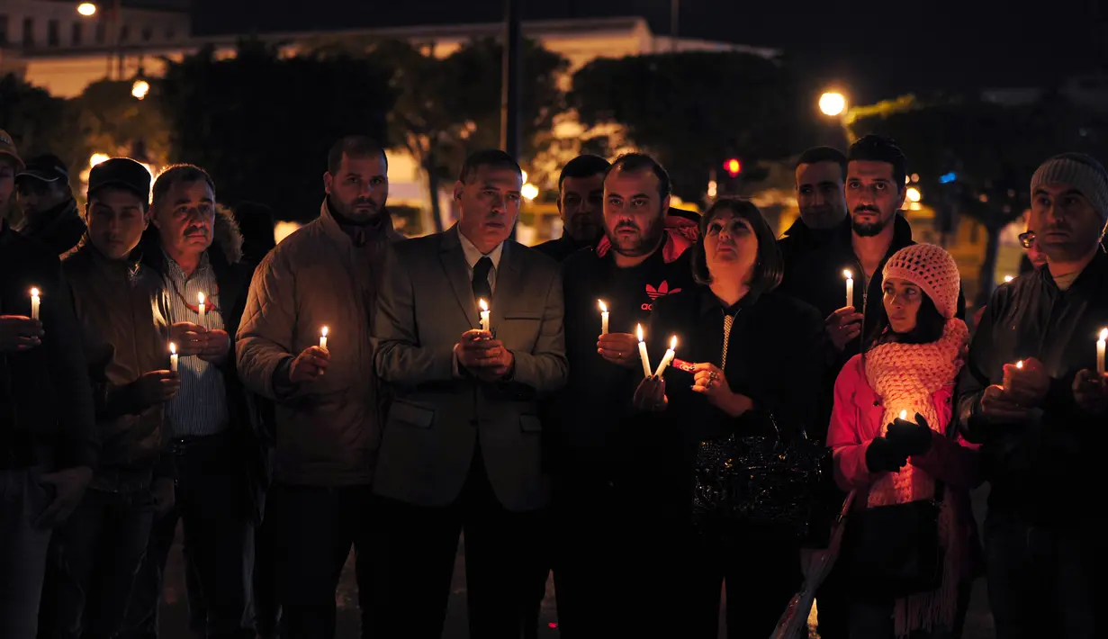 Anggota partai Nidaa Tounes memegang lilin di lokasi ledakan bus yang mengangkut pengawal Presiden Tunisia di Tunis, Selasa (24/11). Insiden yang diduga akibat serangan bom bunuh diri itu menewaskan 12 orang dan melukai 16 lainnya.(AFP PHOTO/Fethi Belaid)