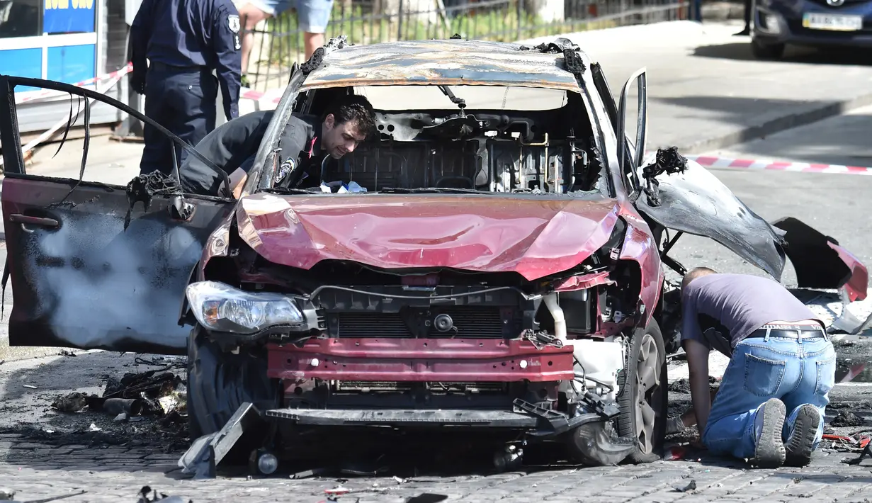 Polisi Ukraina memeriksa bangkai mobil yang ditumpangi jurnalis investigasi ternama, Pavel Sheremet, yang tewas di Kiev, Rabu (20/7). Jurnalis Ukrayina Pravda itu sedang mengendarai mobil ke tempat kerja ketika mobil tersebut meledak (Sergei SUPINSKY/AFP)