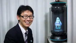 Akihiko Kondo asal Jepang berpose di sebelah hologram aktris virtual, Hatsune Miku seminggu setelah pernikahan mereka di Tokyo, 10 November 2018. Pengalaman traumatis yang terjadi 10 tahun lalu membuat Kondo trauma pada wanita. (Behrouz MEHRI/AFP)