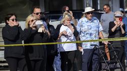 Orang-orang bereaksi melihat puing-puing helikopter Huntington Beach terangkat dari air di Pantai Newport, California (20/2/2022). Pihak berwenang sedang menyelidiki penyebab kecelakaan helikopter polisi di sepanjang pantai California Selatan tersebut. (Mindy Schauer/The Orange County Register via A