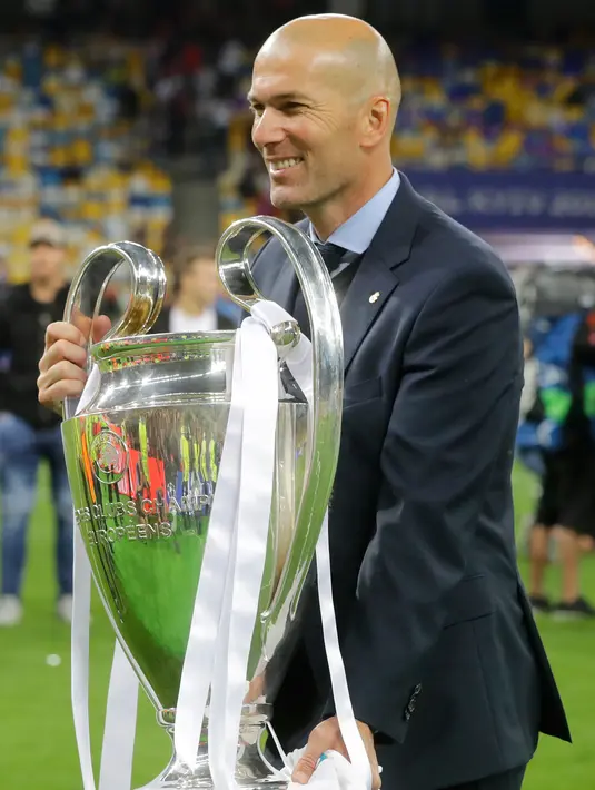 Pelatih Real Madrid Zinedine Zidane memegang trofi usai menjadi juara Liga Champions 2018 di Stadion NSK Olimpiyskiy, Ukraina (26/5). Real Madrid berhasil menjadi juara Liga Champions 2018 usai mengalahkan Liverpool 3-1. (AP/Sergei Grits)