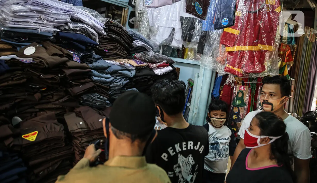 Calon pembeli melihat seragam sekolah di kawasan Pasar Jatinegara, Jakarta, Selasa (30/6/2020). Sejumlah pedagang di tempat itu mengeluhkan omset penjualan seragam sekolah yang menurun hingga 90 persen akibat sepi pembeli dan anjuran belajar di rumah saat  COVID-19. (Liputan6.com/Faizal Fanani)