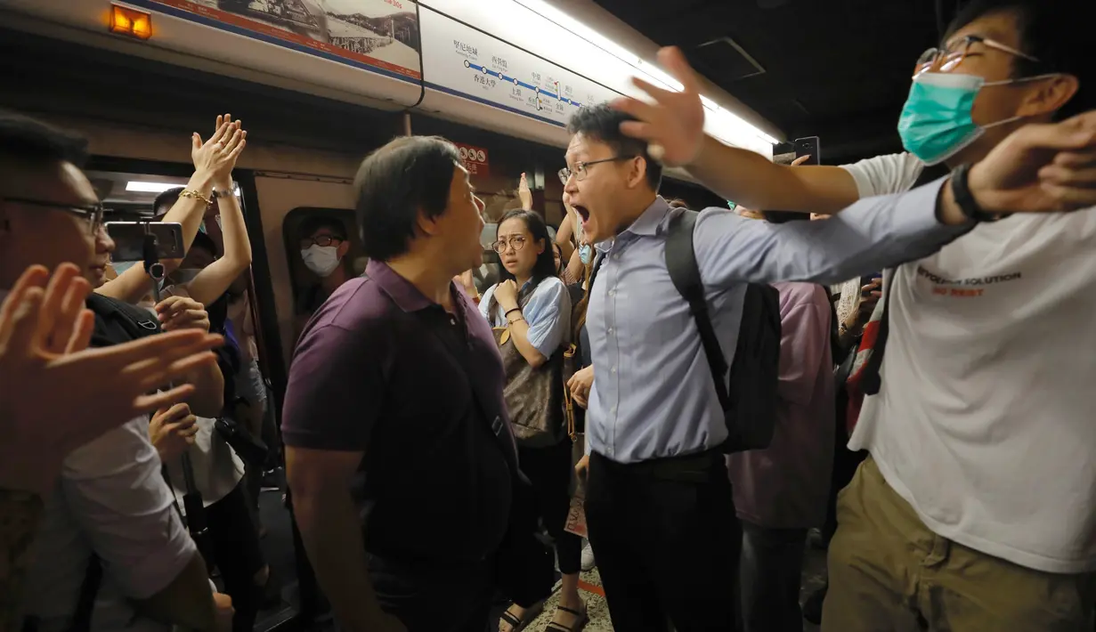 Penumpang berdebat dengan pengunjuk rasa yang mengganggu jalur kereta bawah tanah di Hong Kong (30/7/2019). Pengunjuk rasa telah mengganggu layanan kereta bawah tanah pada pagi hari perjalanan dengan menghalangi pintu-pintu masuk kereta dan mencegah mereka meninggalkan stasiun. (AP Photo/Vincent Yu)