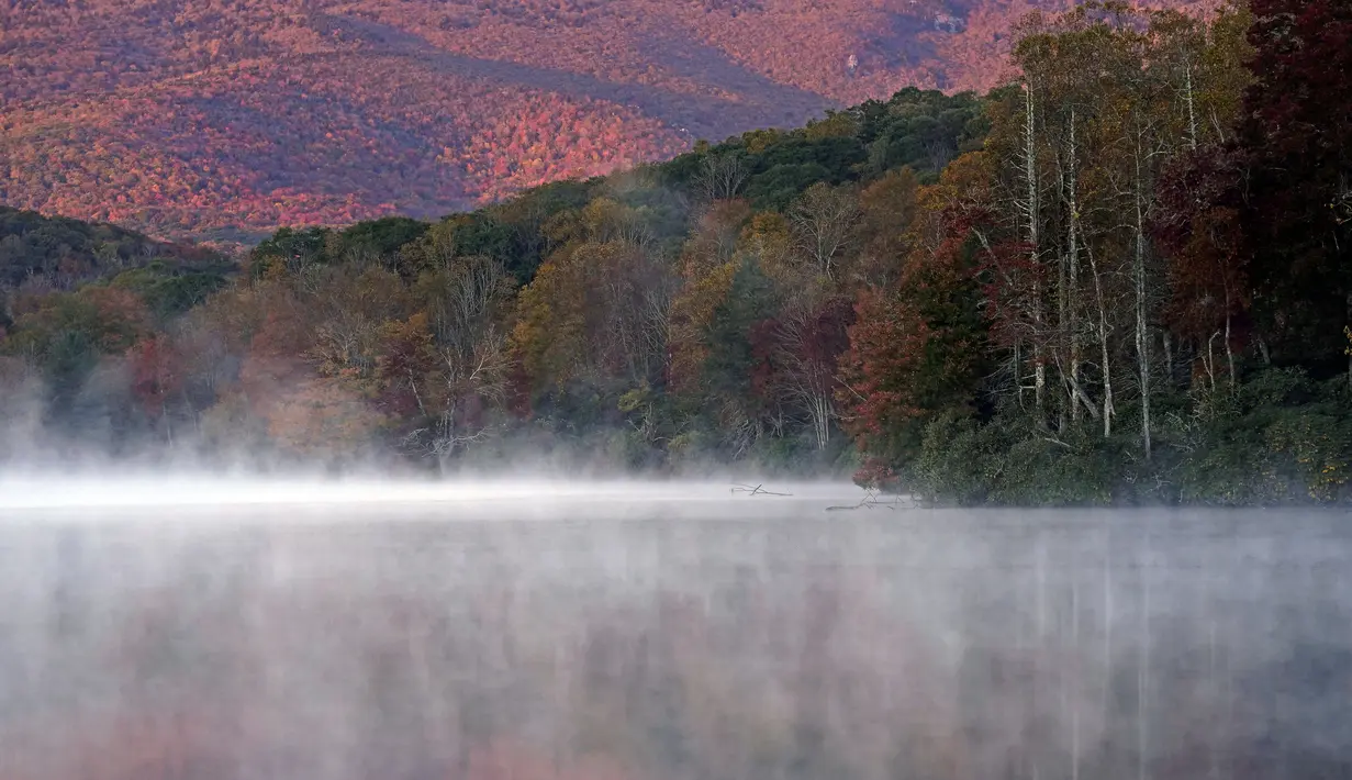 Kabut menyelimuti Price Lake saat Grandfather Mountain bersinar dalam cahaya pagi sementara matahari terbit di sepanjang Blue Ridge Parkway dekat Blowing Rock, North California, pada 19 Oktober 2021. (AP Photo/Gerry Broome)