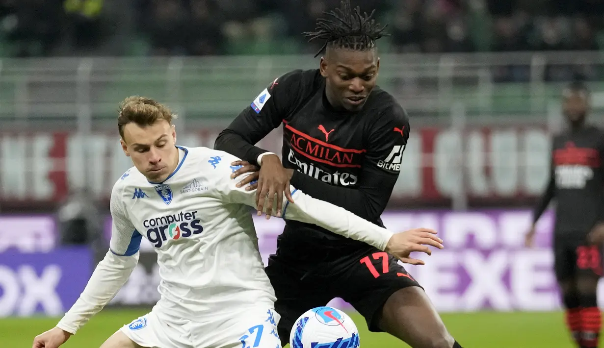 Penyerang AC Milan Rafael Leao berebut bola dengan gelandang Empoli Szymon Zurkowski pada pekan ke-29 Liga Italia di Stadion San Siro, Minggu (13/3/2022) dini hari WIB.  AC Milan menang tipis 1-0 atas tamunya, Empoli. (AP Photo/Antonio Calanni)