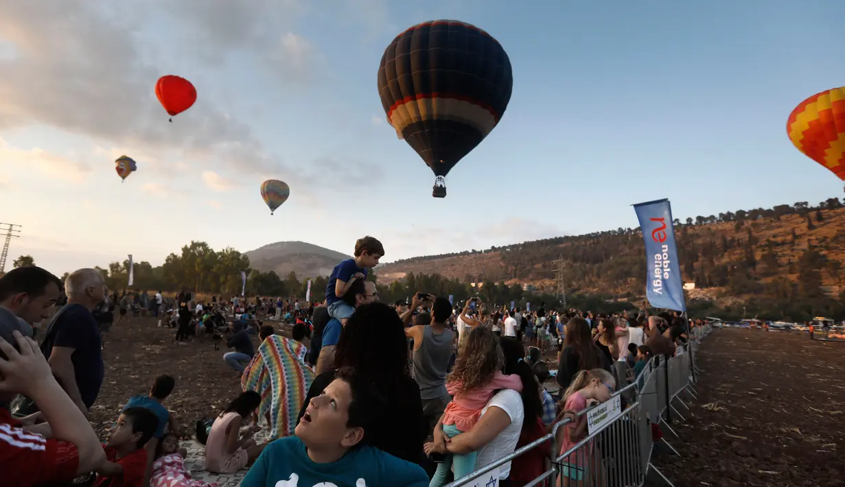 Sejumlah pengunjung menyaksikan Festival Balon Udara Gilboa di dekat Kibbutz Ein Harod, Lembah Jizreel, Israel (4/8). Festival balon udara ini menjadi tontonan menarik bagi warga sekitar dan wisatawan. (AFP Photo/Manahem Kahana)