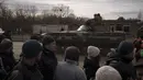 Warga yang mengantre bantuan menyaksikan tentara Ukraina menaiki tank di kota Trostsyanets, Ukraina, Senin, 28 Maret 2022. Trostsyanets baru-baru ini direbut kembali oleh pasukan Ukraina setelah dikuasai oleh Rusia sejak awal perang. (AP Photo/Felipe Dana)