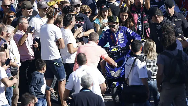 Valentino Rossi gagal memenangi gelar juara dunia MotoGP 2015 karena hanya finis di posisi 4 pada seri terakhir di Valencia, Minggu (8/11/2015). Namun, ratusan orang menyambut Rossi kembali ke paddock seolah ia yang menjadi juara dunia.