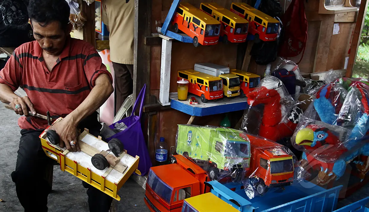 Pedagang memperbaiki mobil kayu yang akan di jual di kios mainan kayu, Jakarta (27/5/2015). Produksi mainan lokal dan tradisional diharapkan mampu bertahan, mengingat pasar bebas Asean yang dimulai Januari 2016 mendatang. (Liputan6.com/Johan Tallo)