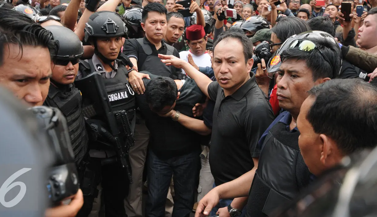 Petugas kepolisian menggiring salah satu tersangka perampokan disertai penyanderaan di Kawasan Pondok Indah, Jakarta, Minggu (3/9). Perampokan disertai penyanderaan terjadi sejak Minggu (3/9) pagi. (Liputan6.com/Helmi Fithriansyah)