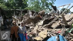 Warga Bukit Duri melintas di pinggir bangunan yang telah dirobohkan Satpol PP, Jakarta, Kamis (29/9). Pemprov DKI lanjutkan pembongkaran belasan rumah di Bukit Duri yang belum sempat dibongkar kemarin. (Liputan6.com/Yoppy Renato)