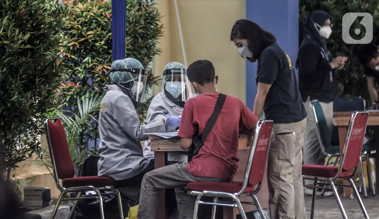 Tenaga kesehatan melakukan tes usap COVID-19 kepada keluarga korban Sriwijaya Air SJ 182 sebelum memberikan data di Posko Ante Mortem DVI, RS Polri, Jakarta, Minggu (10/1/2020).Keluarga korban mulai berdatangan ke posko ante mortem pascajatuhnya Sriwijaya Air SJ 182. (merdeka.com/Iqbal S. Nugroho)