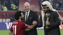 Presiden FIFA Gianni Infantino (tengah) menyaksikan Sheikh Joaan bin Hamad bin Khalifa Al Thani (kanan) berjabat tangan dengan penyerang Liverpool, Mohamed Salah setelah pertandingan antara Liverpool melawan Flamengo di Stadion Internasional Khalifa, Doha, Qatar (22/12/2019). (AP Photo/Hassan Ammar)