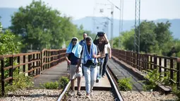 Sejumlah pria berjalan menyusuri rel kereta api saat perjalanan menuju Gevgelija, wilayah perbatasan Macedonia-Yunani, Kamis (9/7/2015). Mereka menempuh ribuan kilometer agar dapat mengejar kereta api tujuan Serbia. (AFP PHOTO/Robert ATANASOVSKI)