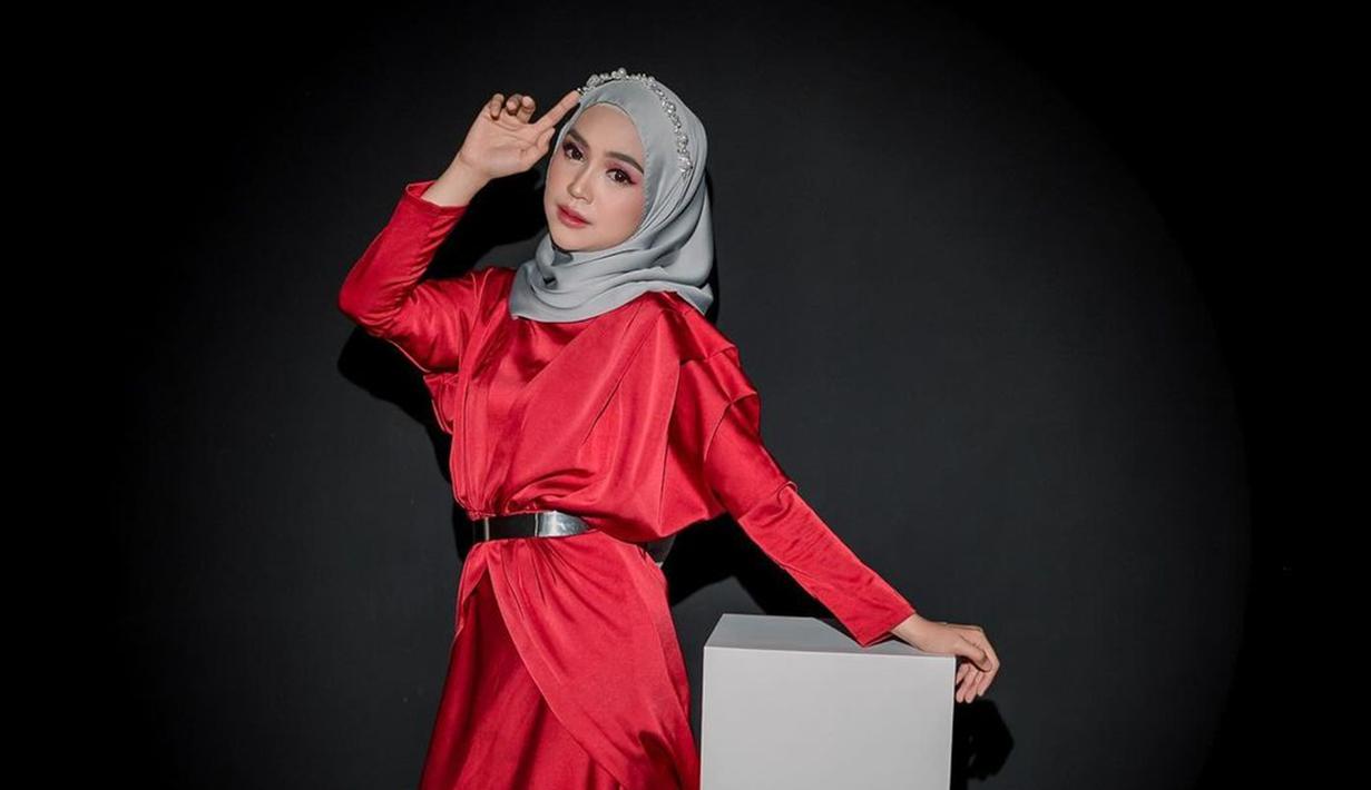 Begini detail penampilan Ria Ricis saat jalani pemotretan bareng buah hatinya. Gaya berpakaian Ria Ricis ini merupakan styling dari fashion stylish Doley Tobing. Tema makeup cocok dengan busana yang dikenakannya, wajah Ricis dipoles oleh MUA Sabil Makeup. Berfoto dengan busana merah dan latar hitam, warna hijab abu-abu cocok dikenakan oleh Ricis. (Liputan6.com/IG/@riaricis1795)