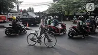 Pengendara motor dan sepeda melintas dekat kendaraan taktis TNI dan Polri saat penyekatan PPKM Darurat di kawasan Lampiri, Kalimalang, Jakarta, Senin (5/7/2021). Penyekatan ini dilakukan untuk membatasi pergerakan di perbatasan Jakarta guna memutus penyebaran COVID-19. (merdeka.com/Iqbal S. Nugroho)