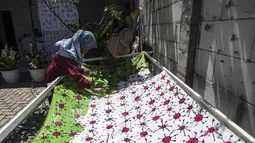 Penyandang disabilitas menjemur kain batik dengan motif virus corona di Surabaya, Jawa Timur (19/8/2020). Di tengah pandemi Covid-19, sekelompok penyandang disabilitas di Surabaya membuat batik bermotifkan virus corona. (AFP/JUNI KRISWANTO)