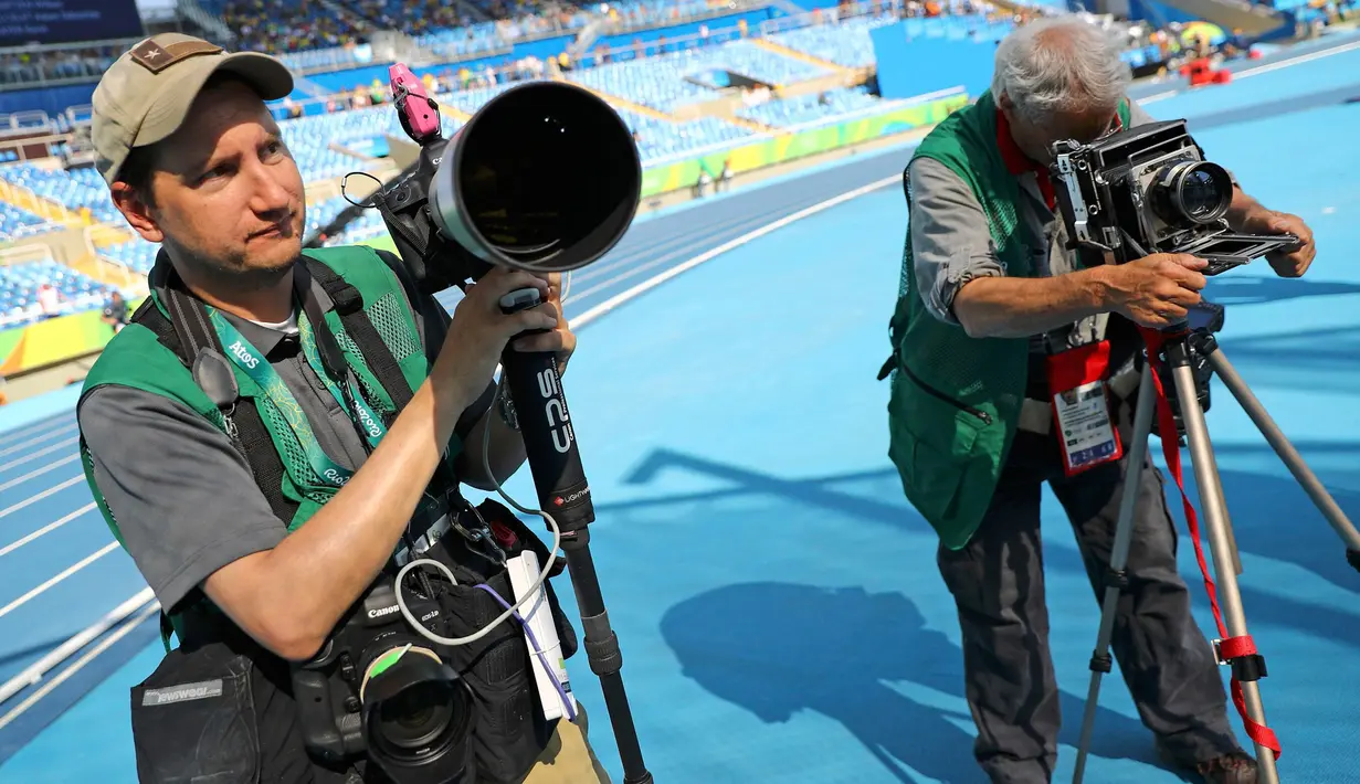 Fotografer David Burnett (kanan) mengatur kamera dengan kecepatan 4x5 inci bersama fotografer Matt Slocum sebelum berlangsungnya cabang atletik Olimpiade Rio 2016 di Olympic Stadium, Rio de Janeiro, Brasil, (15/8). (REUTERS/Kai Pfaffenbach)