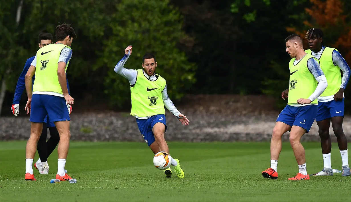 Gelandang Chelsea, Eden Hazard (tengah) menggiring bola saat mengikuti sesi latihan tim di Chelsea Training Ground, di Cobham, Surrey (22/5/2019). Chelsea akan bertanding melawan Arsenal pada babak Final Liga Europa pada 29  Mei di Baki Olimpiya Stadionu. (AFP Photo/Ben Stansall)