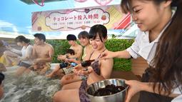 Petugas memberikan cokelat kepada pengunjung saat mandi spa cokelat di Hakone, Jepang, Senin (13/2). Mandi spa cokelat ini digelar setiap tahun bulan Februari. (AFP PHOTO / Kazuhiro Nogi)