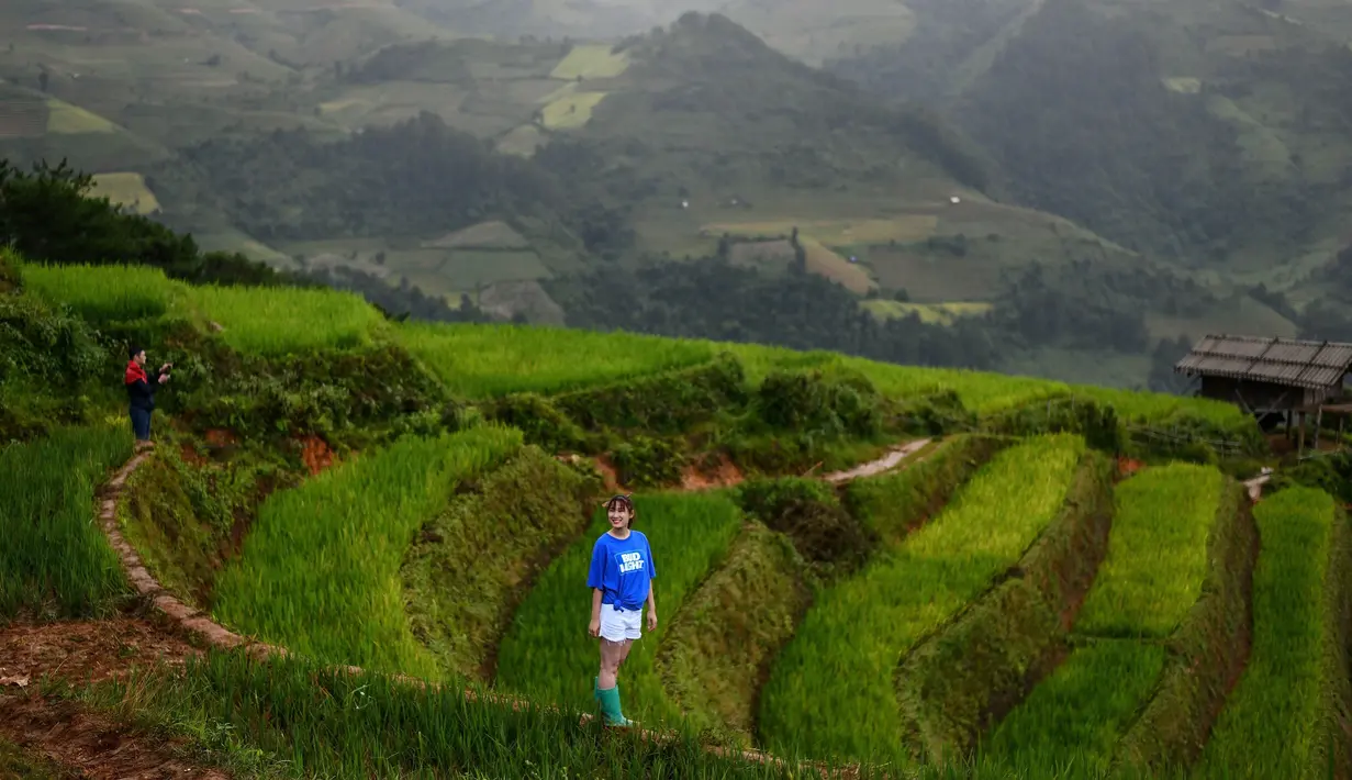 Seorang perempuan berfoto dengan latar belakang sawah terasering di distrik Mu Cang Chai, Vietnam pada 18 September 2020. Pesawahan terasering di Mu Cang Chai merupakan destinasi-destinasi wisata yang atraktif dan menyerap kedatangan banyak wisatawan domestik dan mancanegara. (Manan VATSYAYANA/AFP)