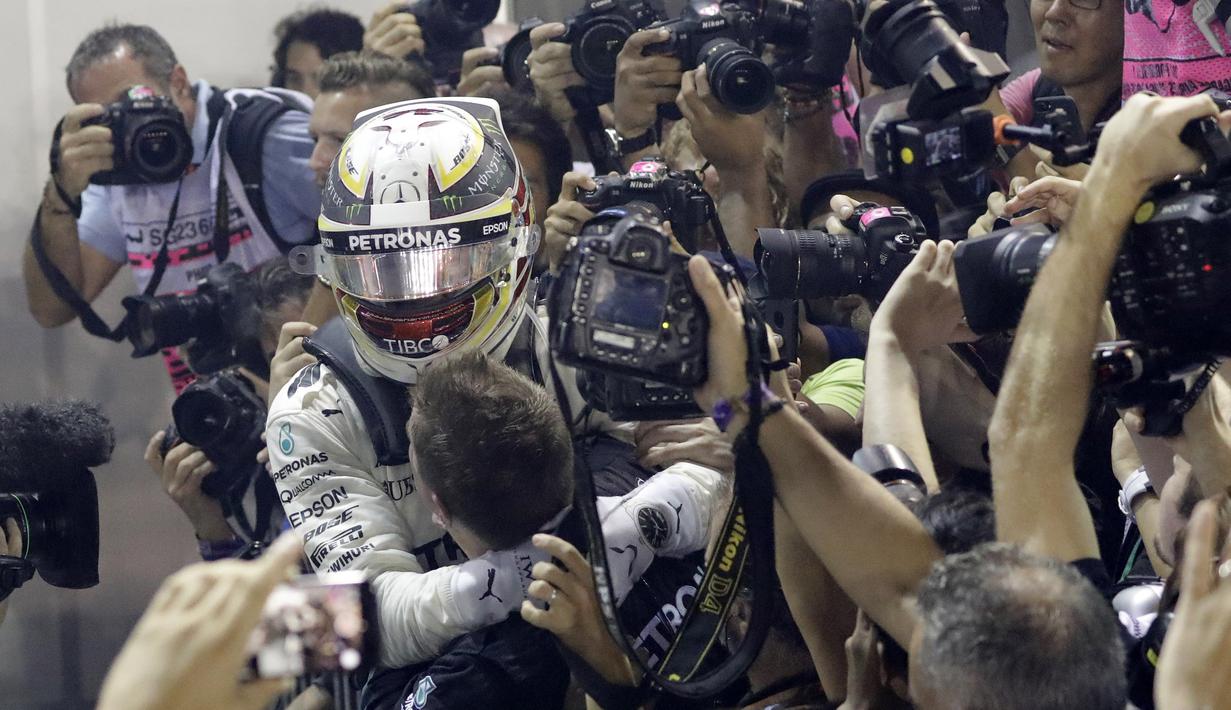 Pebalap Mercedes, Lewis Hamilton merayakan kemenangan bersama tim mekanik pada balapan F1 GP Singapura di  Marina Bay City Circuit, (17/9/2017). Hamilton kini memiliki total poin 263. (AP/Wong Maye-E)