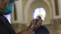 Seorang petugas kesehatan menyiapkan vaksin COVID-19 produksi AstraZeneca di dalam gereja Paroki Hati Kudus Yesus di Quezon City, Filipina, Senin (17/5/2021). Gereja itu digunakan untuk mempercepat proses vaksinasi kepada warga di daerah tersebut. (AP Photo/Aaron Favila)